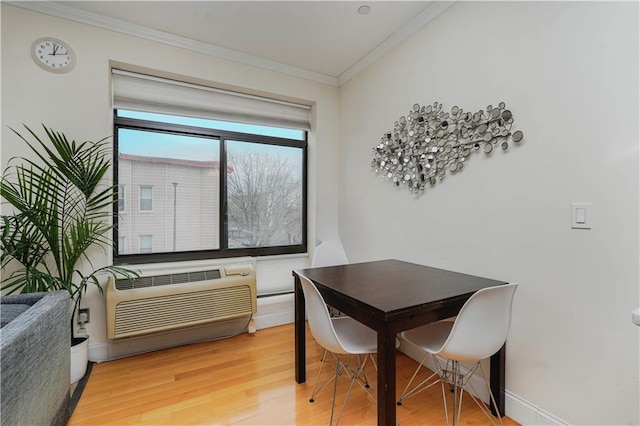 dining room with ornamental molding, an AC wall unit, light wood finished floors, and baseboards