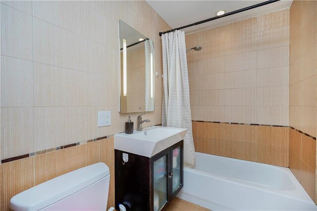 full bathroom with shower / tub combo with curtain, vanity, toilet, and tile walls