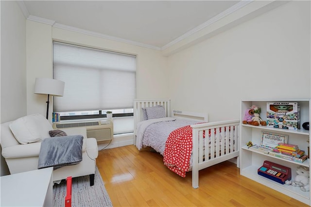 bedroom with ornamental molding, wood finished floors, and a wall mounted air conditioner