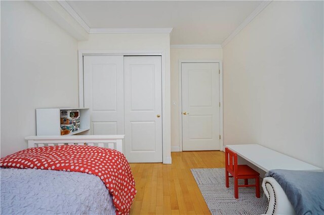 bedroom featuring light wood-type flooring, crown molding, and a closet