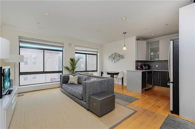 living area featuring ornamental molding, recessed lighting, light wood-style flooring, and a toaster