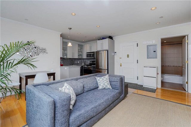 living room featuring ornamental molding, recessed lighting, electric panel, and light wood-style floors