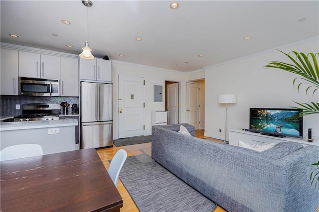 living area with crown molding, recessed lighting, electric panel, and light wood-style floors