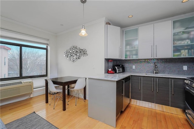 kitchen featuring a sink, light wood-style floors, backsplash, dishwasher, and crown molding