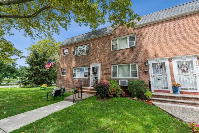 multi unit property with brick siding, roof with shingles, and a front yard