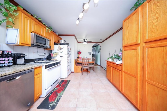 kitchen with arched walkways, light tile patterned floors, appliances with stainless steel finishes, ornamental molding, and backsplash