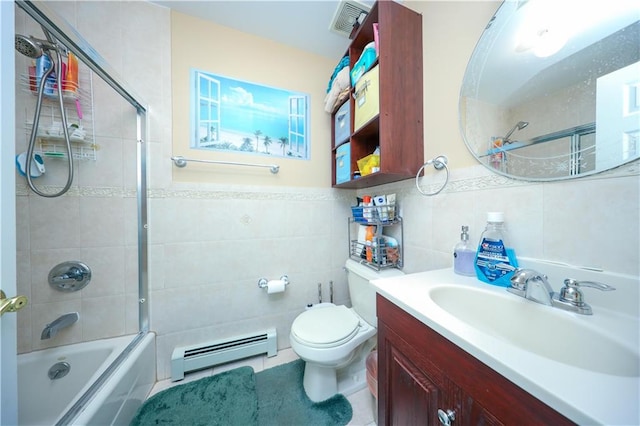 full bathroom featuring toilet, bath / shower combo with glass door, vanity, tile walls, and baseboard heating