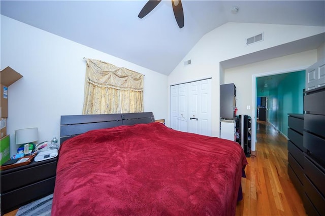 bedroom with ceiling fan, high vaulted ceiling, wood finished floors, visible vents, and a closet