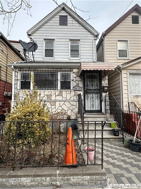 exterior space with a fenced front yard and stone siding