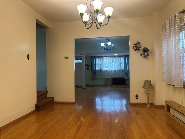 unfurnished dining area with an inviting chandelier, baseboards, and wood finished floors