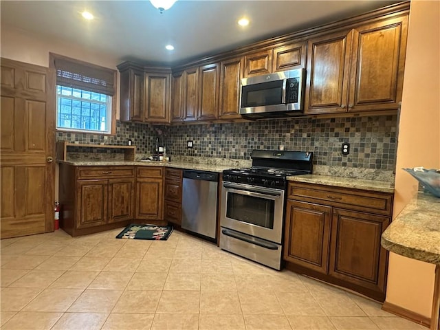 kitchen featuring recessed lighting, backsplash, appliances with stainless steel finishes, light tile patterned flooring, and light stone countertops