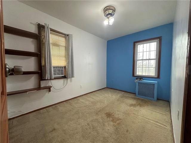 spare room featuring carpet floors, cooling unit, radiator, and baseboards