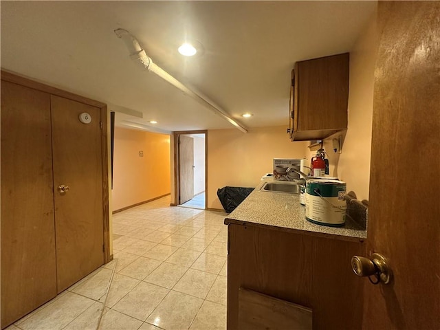 kitchen featuring light tile patterned floors, recessed lighting, a sink, light countertops, and brown cabinets