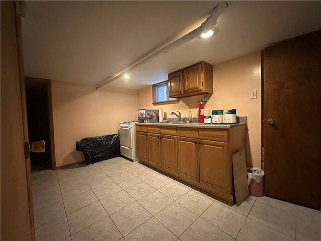 kitchen with light tile patterned floors, brown cabinetry, a sink, and light countertops