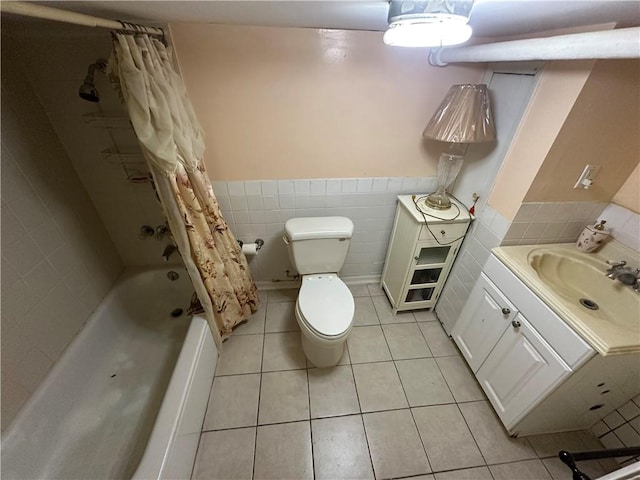 bathroom featuring a wainscoted wall, tile walls, toilet, shower / bath combo with shower curtain, and tile patterned floors