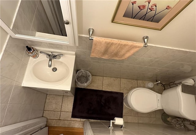 bathroom featuring a sink, tile walls, and toilet