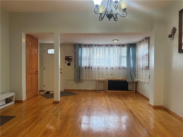 entryway featuring a chandelier, radiator, baseboards, and wood finished floors