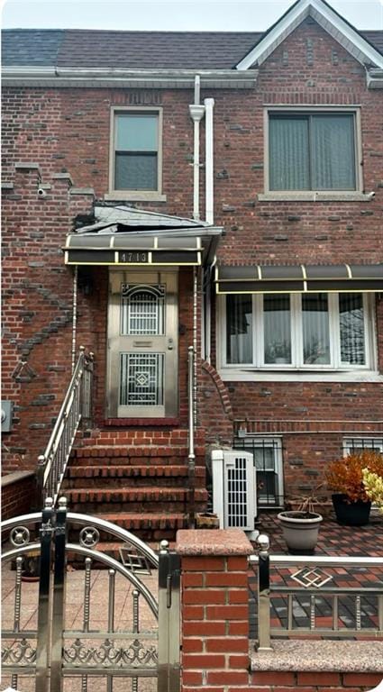 view of property featuring brick siding and roof with shingles