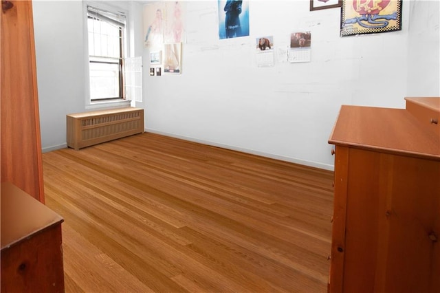 interior space with radiator, baseboards, and wood finished floors