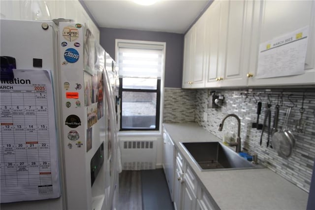 kitchen featuring white cabinetry, light countertops, freestanding refrigerator, and a sink