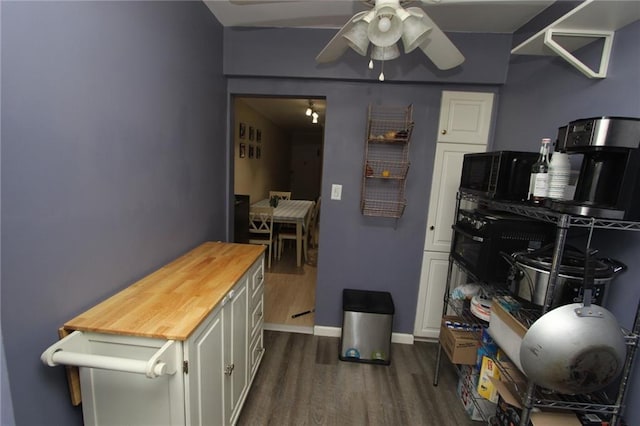 kitchen featuring dark wood-type flooring, ceiling fan, baseboards, white cabinetry, and wood counters