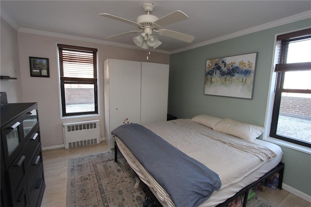 bedroom featuring multiple windows, radiator, light wood-type flooring, and crown molding