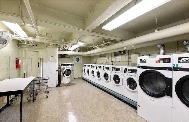 common laundry area with concrete block wall and separate washer and dryer