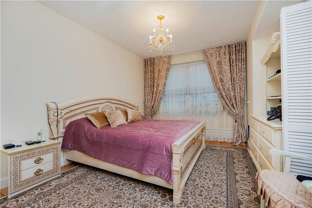 bedroom featuring a chandelier and wood finished floors