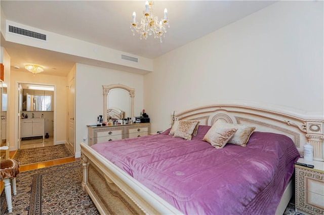 bedroom with an inviting chandelier, wood finished floors, visible vents, and connected bathroom