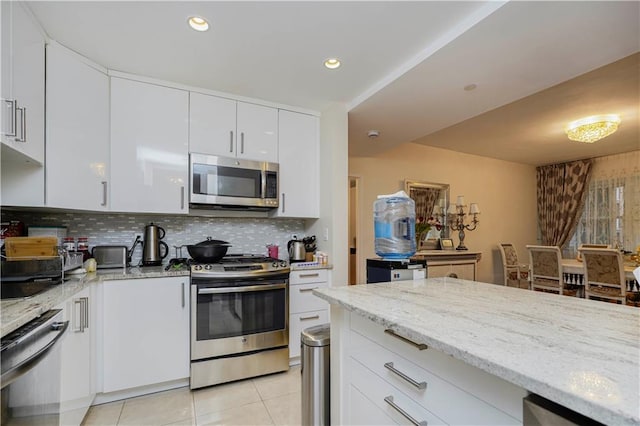 kitchen featuring backsplash, stainless steel appliances, white cabinets, light tile patterned floors, and light stone countertops