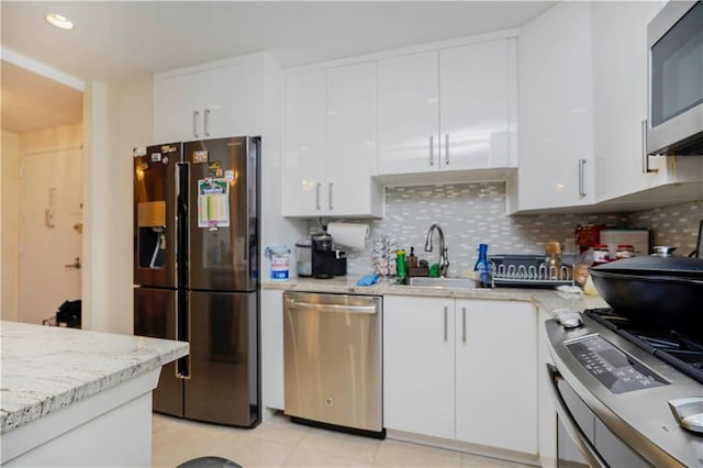 kitchen with a sink, stainless steel appliances, backsplash, and white cabinets