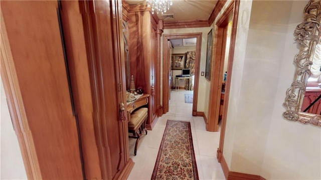 hallway with ornamental molding, visible vents, baseboards, and light tile patterned floors