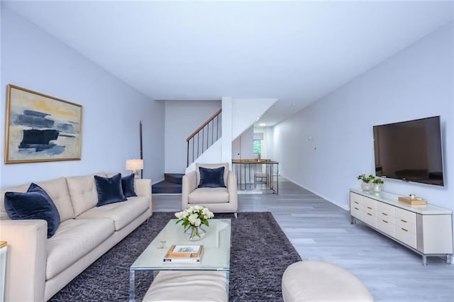 living room featuring light wood-style flooring, stairs, and baseboards