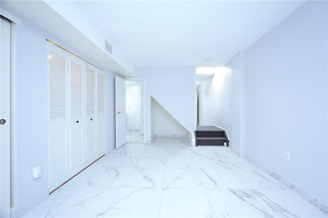 unfurnished bedroom with a closet, marble finish floor, and visible vents