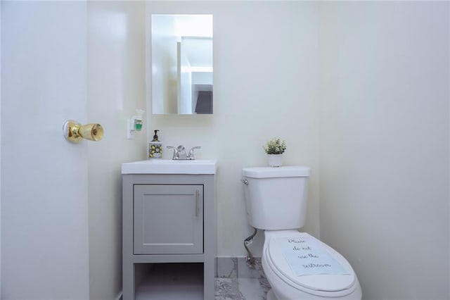 half bath featuring toilet, marble finish floor, and vanity