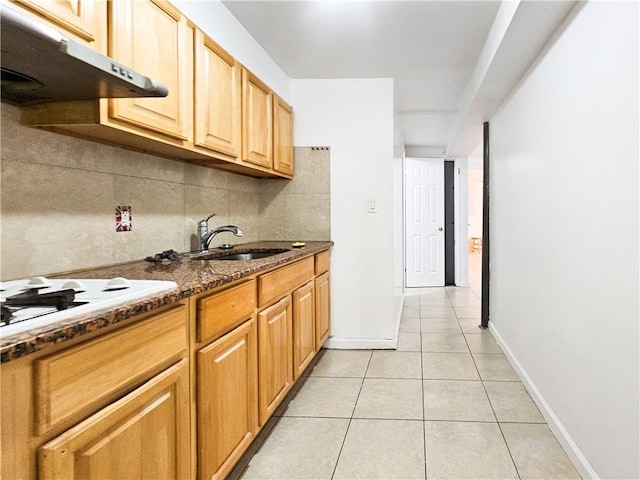 kitchen with light tile patterned flooring, under cabinet range hood, white stovetop, a sink, and decorative backsplash