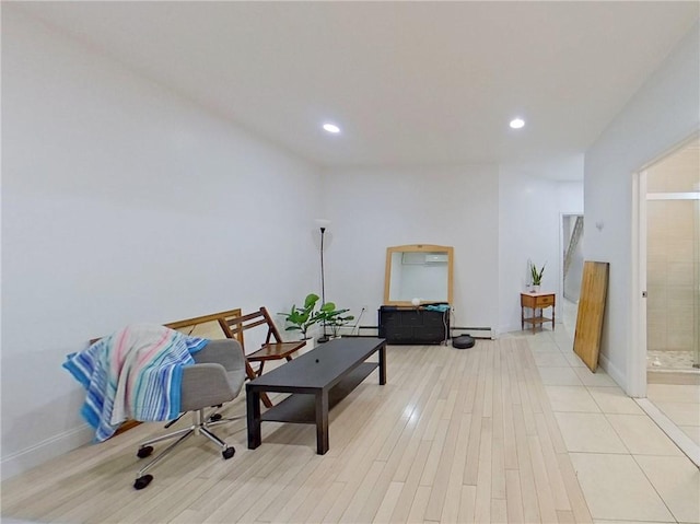 living area featuring baseboards, baseboard heating, light wood-type flooring, and recessed lighting