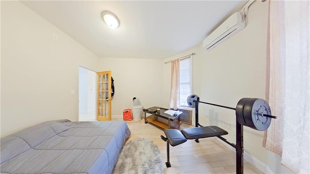 bedroom with a wall unit AC, wood finished floors, and baseboards