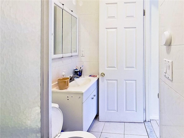 bathroom with tasteful backsplash, toilet, tile patterned flooring, vanity, and tile walls