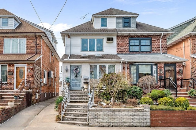 american foursquare style home featuring a wall mounted air conditioner and roof with shingles