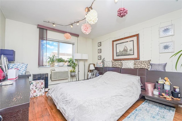 bedroom featuring track lighting and wood finished floors