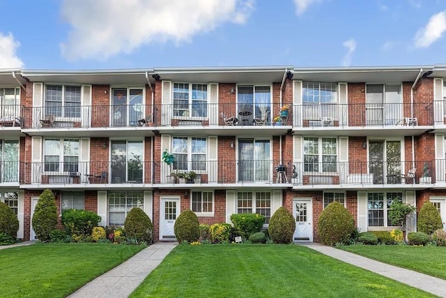 townhome / multi-family property featuring brick siding and a front lawn