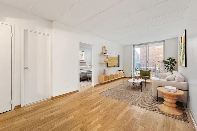 sitting room with expansive windows, baseboards, and wood finished floors