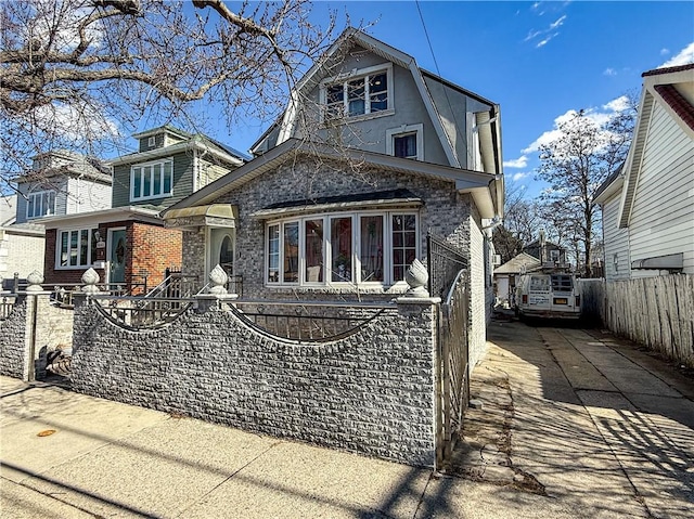 view of front facade featuring driveway, brick siding, and a fenced front yard