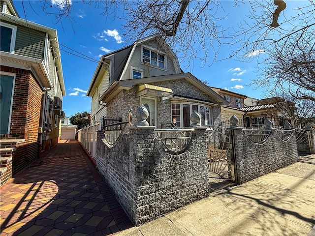 view of front of house featuring a fenced front yard, a gate, and a gambrel roof