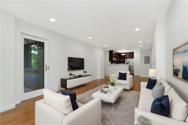 living area featuring electric panel, recessed lighting, light wood-type flooring, and baseboards