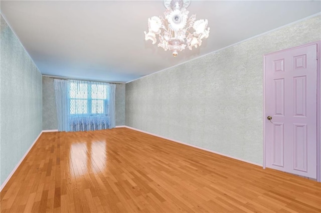 empty room with a chandelier and light wood-type flooring