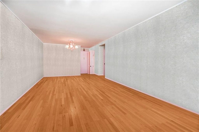 empty room with hardwood / wood-style floors and an inviting chandelier