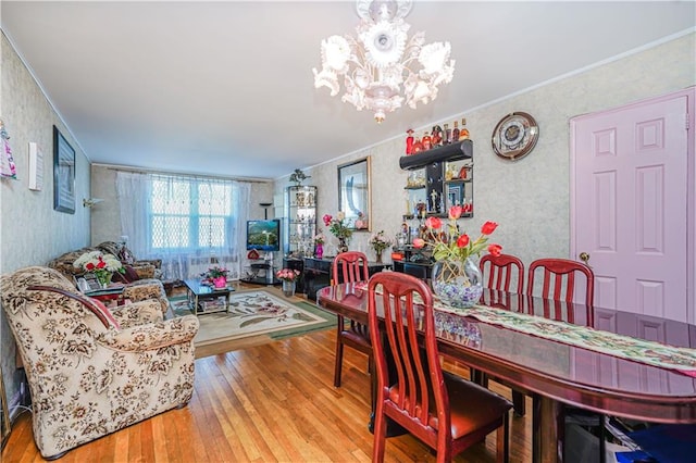 dining area with ornamental molding, hardwood / wood-style floors, and a notable chandelier