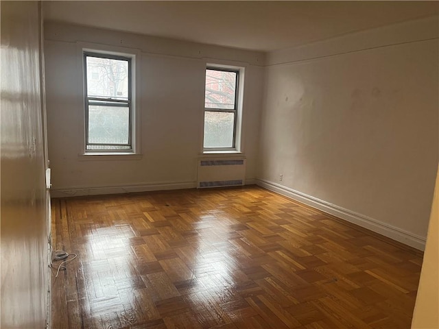 unfurnished room with radiator heating unit and baseboards